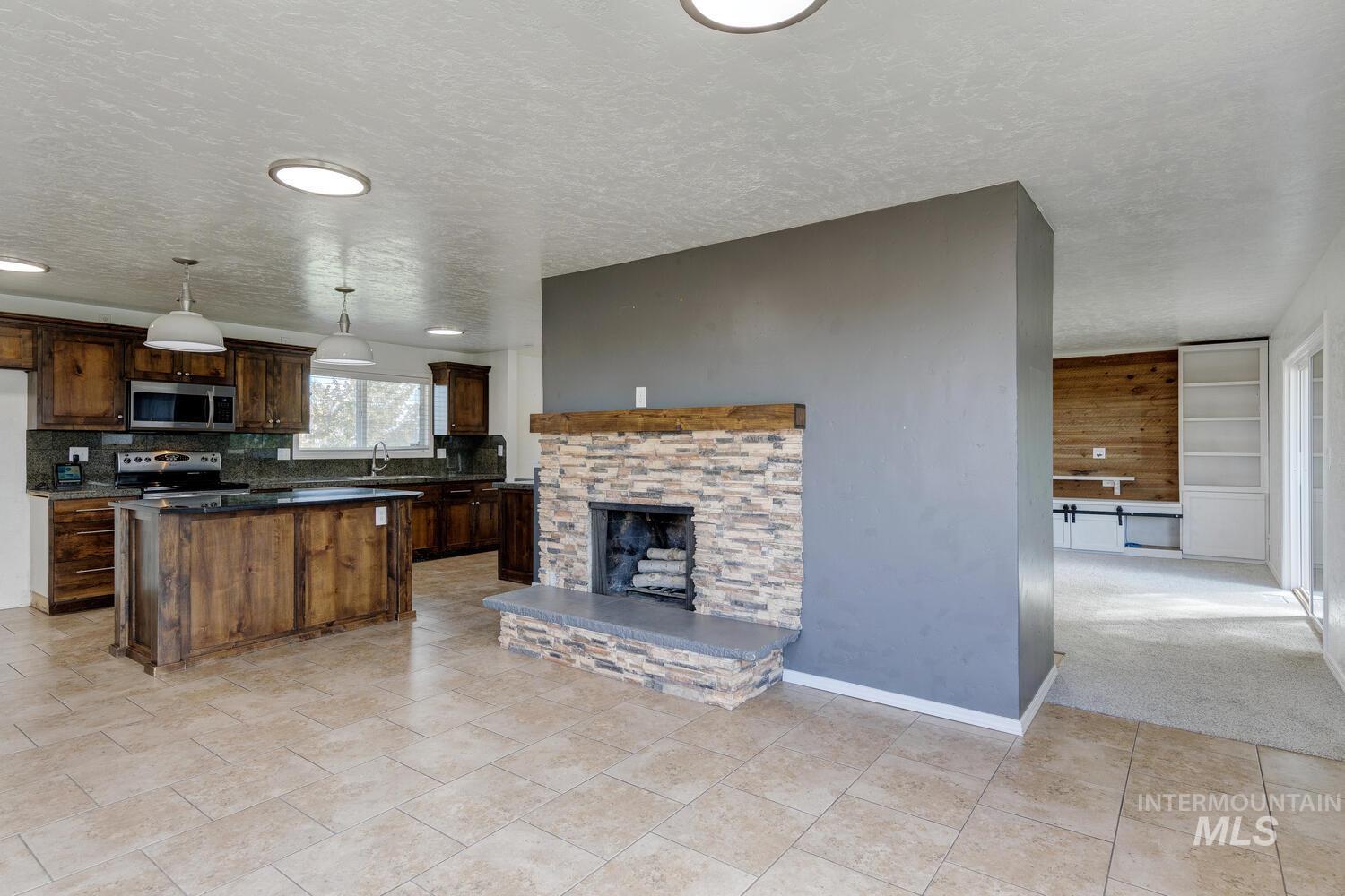 Kitchen featuring pendant lighting, a textured ceiling, backsplash, stainless steel appliances, and dark brown cabinets