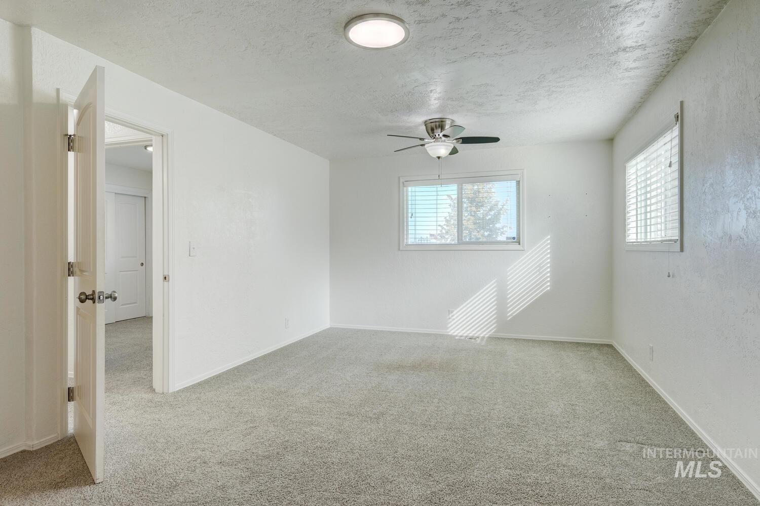 Spare room with light carpet, a textured ceiling, and a ceiling fan