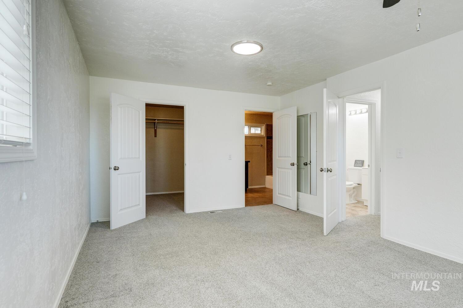 Unfurnished bedroom with a walk in closet, light carpet, and a textured ceiling