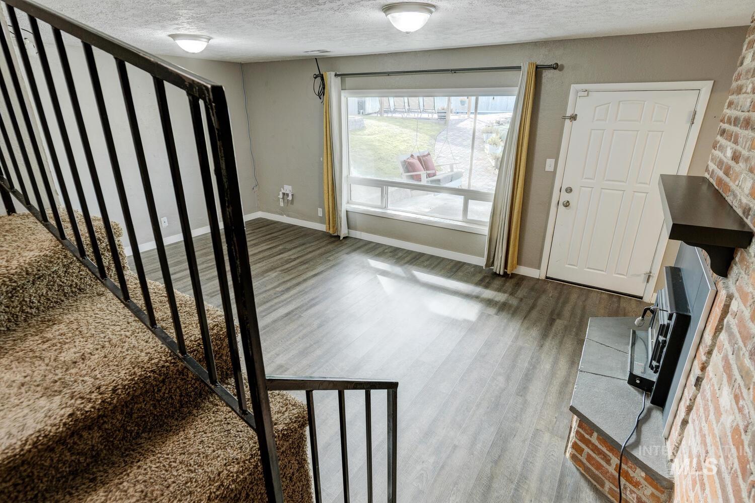Foyer entrance with wood finished floors, stairway, a textured ceiling, and a wood stove