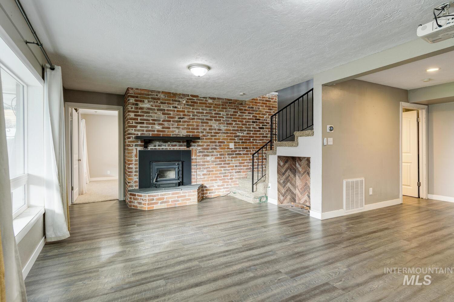 Unfurnished living room with wood finished floors, a textured ceiling, and stairs