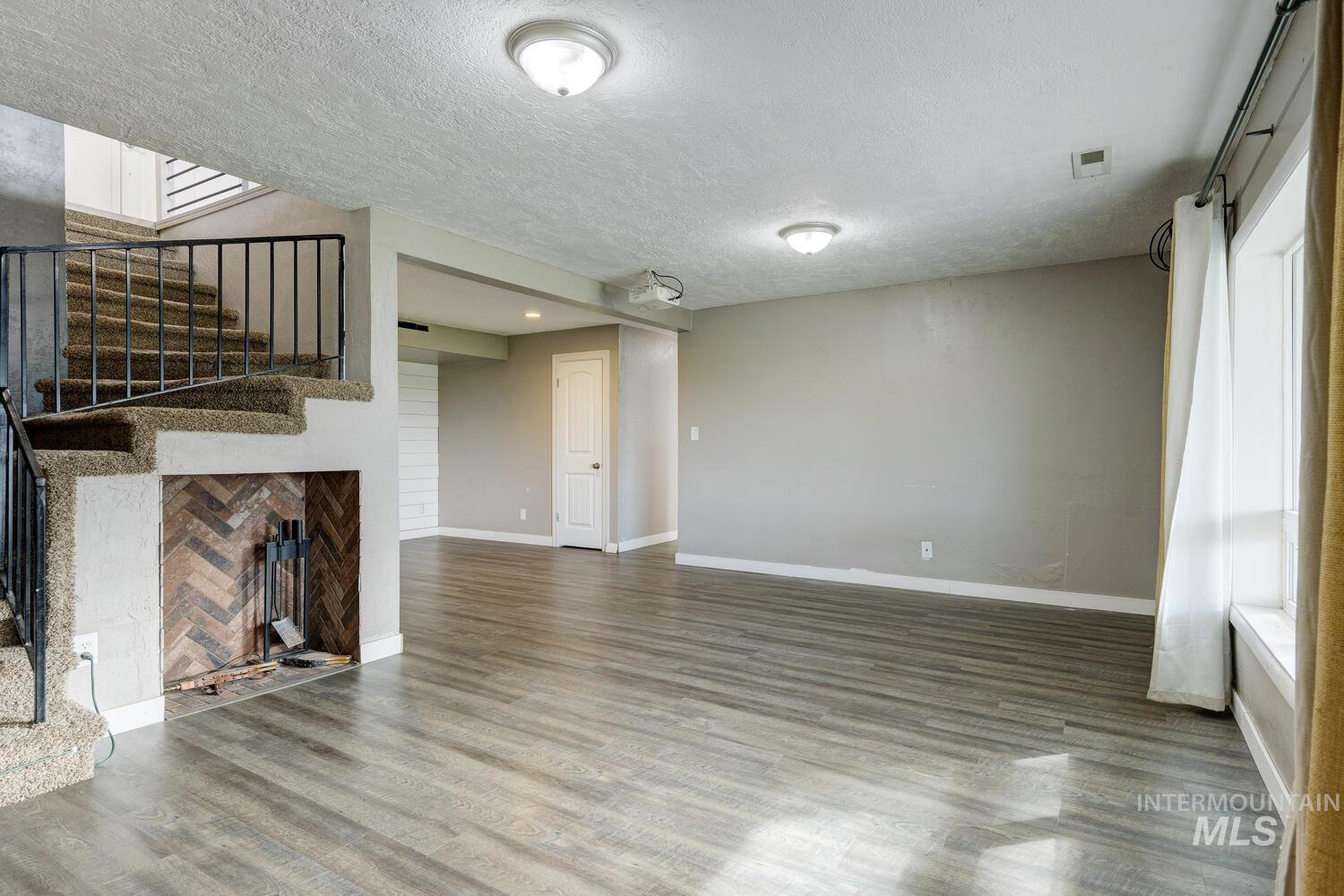 Unfurnished living room featuring wood finished floors, a textured ceiling, stairway, and a barn door