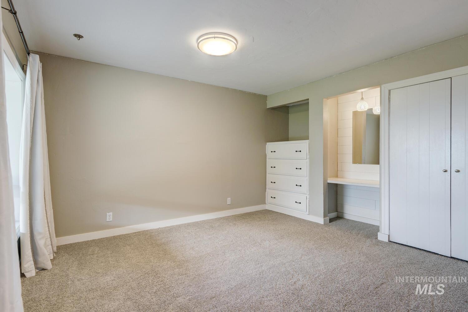 Unfurnished bedroom featuring light carpet and baseboards