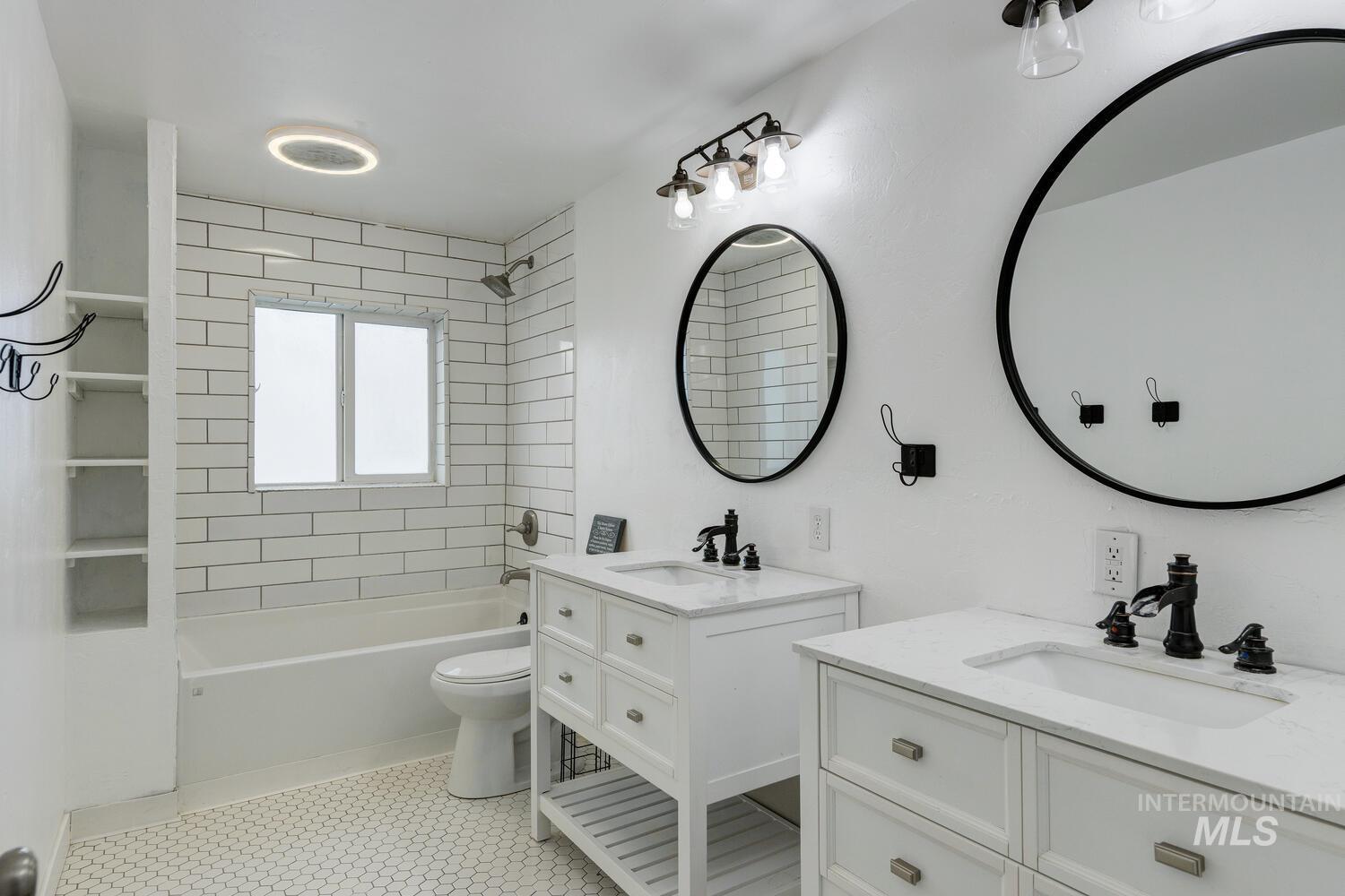 Bathroom featuring two vanities, shower / bath combination, and light tile patterned floors