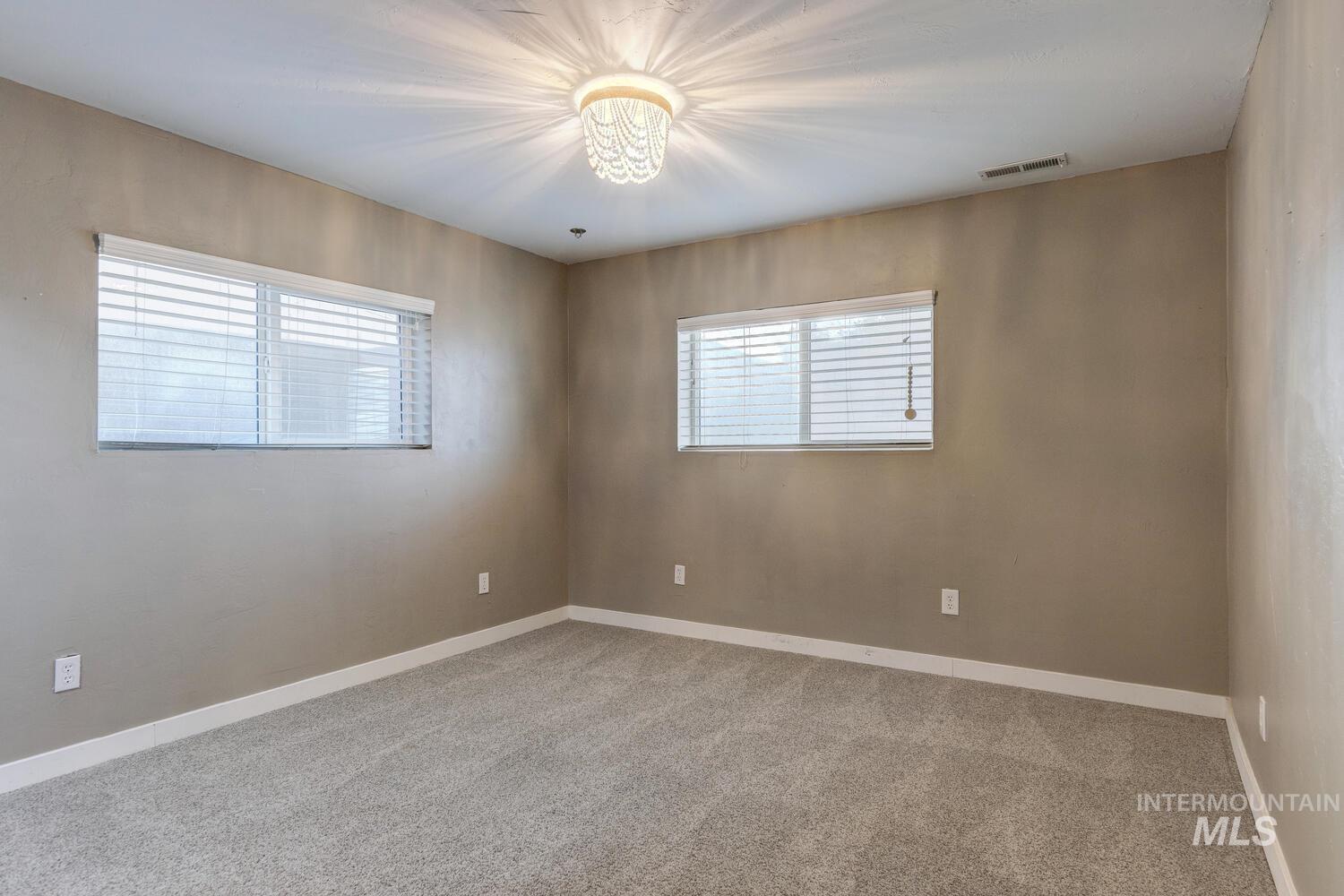 Empty room featuring light colored carpet and baseboards