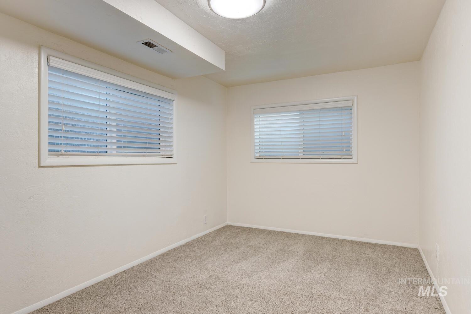 Empty room featuring light carpet and baseboards
