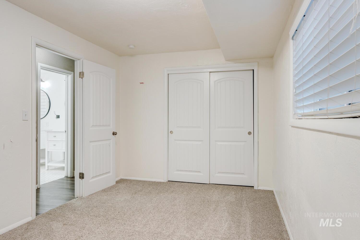 Unfurnished bedroom with light carpet and a closet