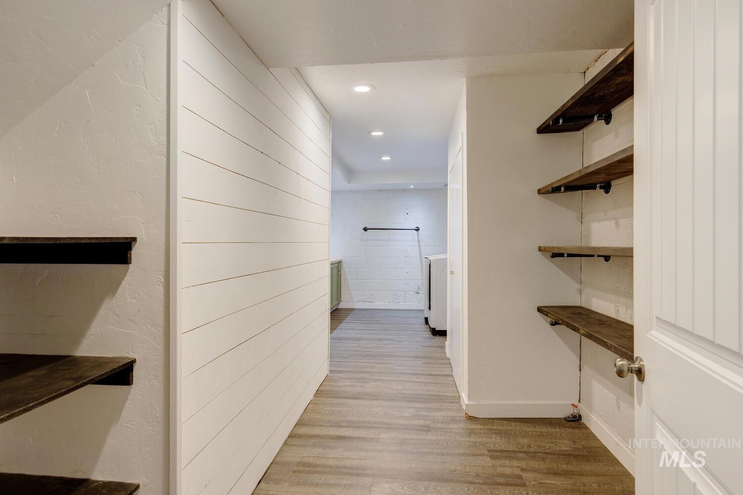 Corridor featuring light wood-style flooring, recessed lighting, and a textured wall