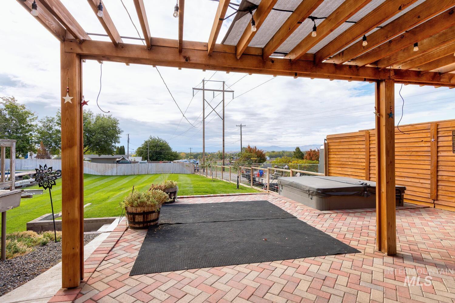 Fenced backyard with a hot tub, a pergola, and a patio