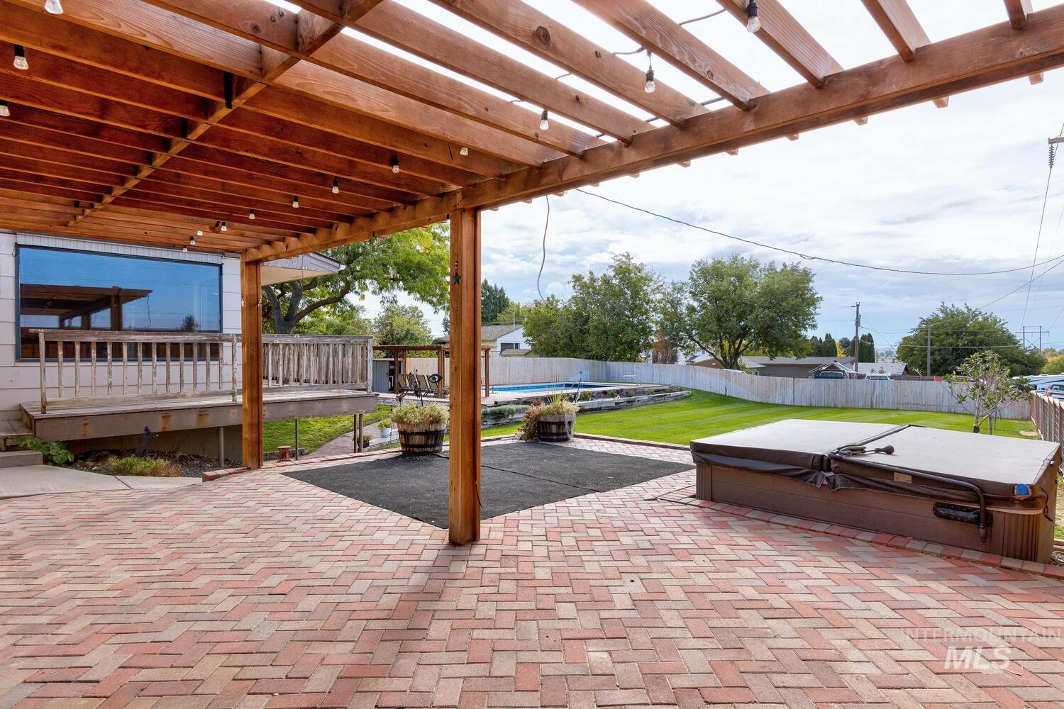 Fenced backyard featuring a hot tub and a patio