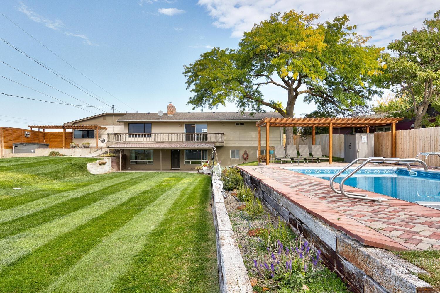 Rear view of property featuring a patio area, a pergola, a lawn, and a chimney
