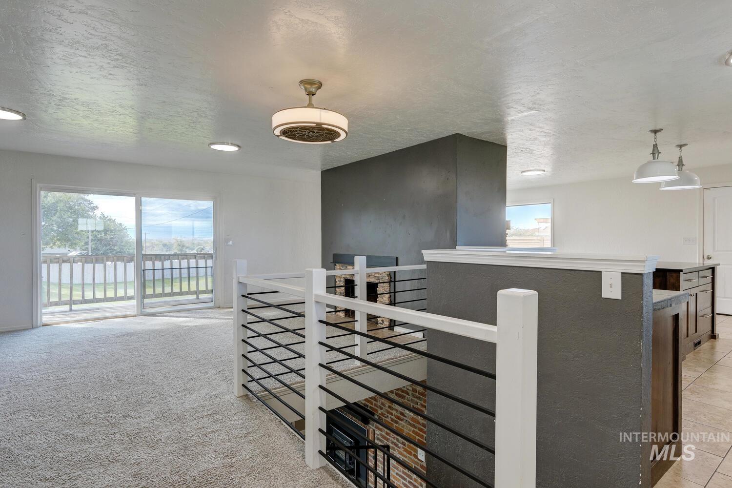 Hall with a textured ceiling, an upstairs landing, and light colored carpet