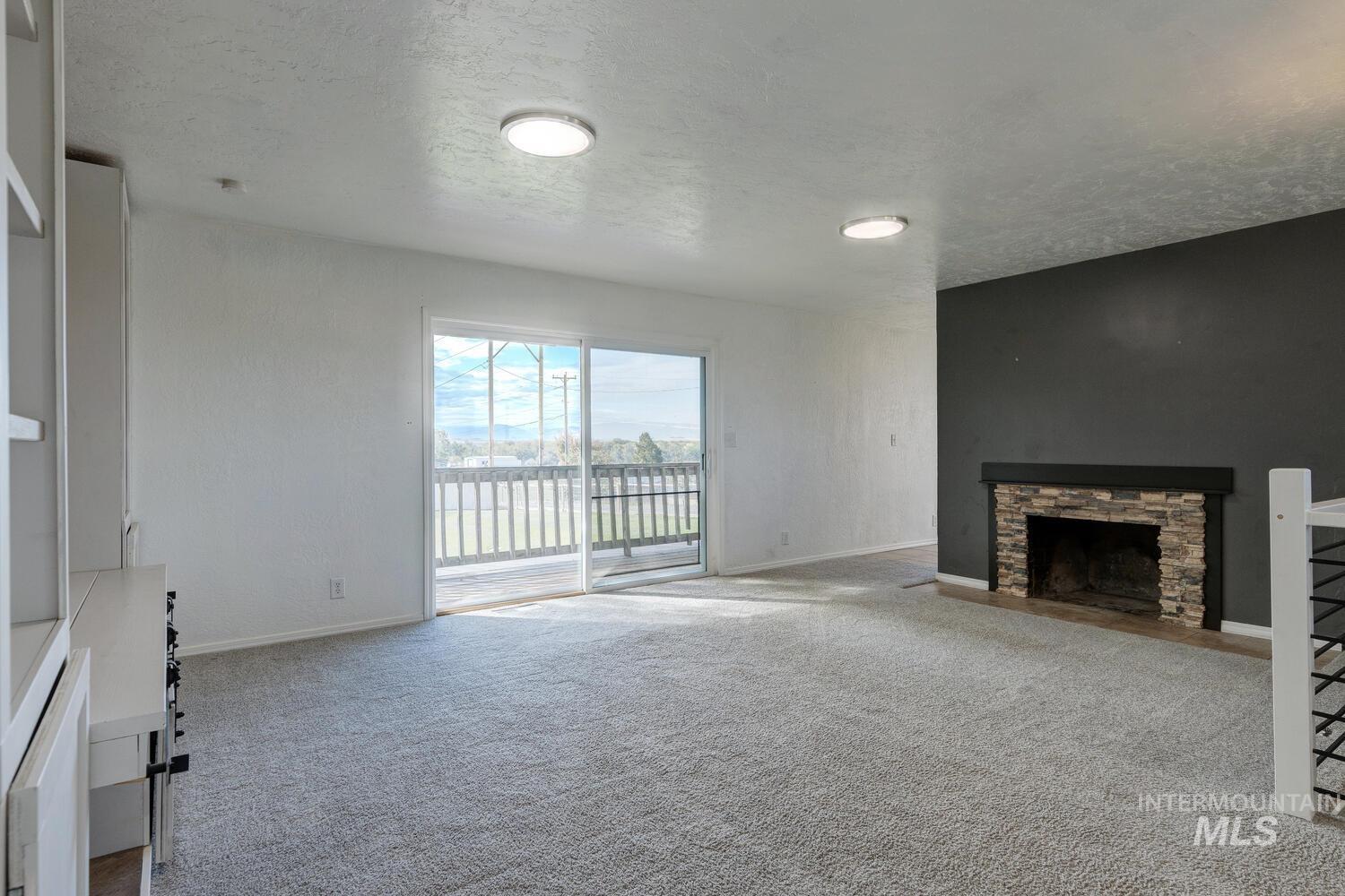 Unfurnished living room with a textured ceiling, carpet flooring, and a fireplace