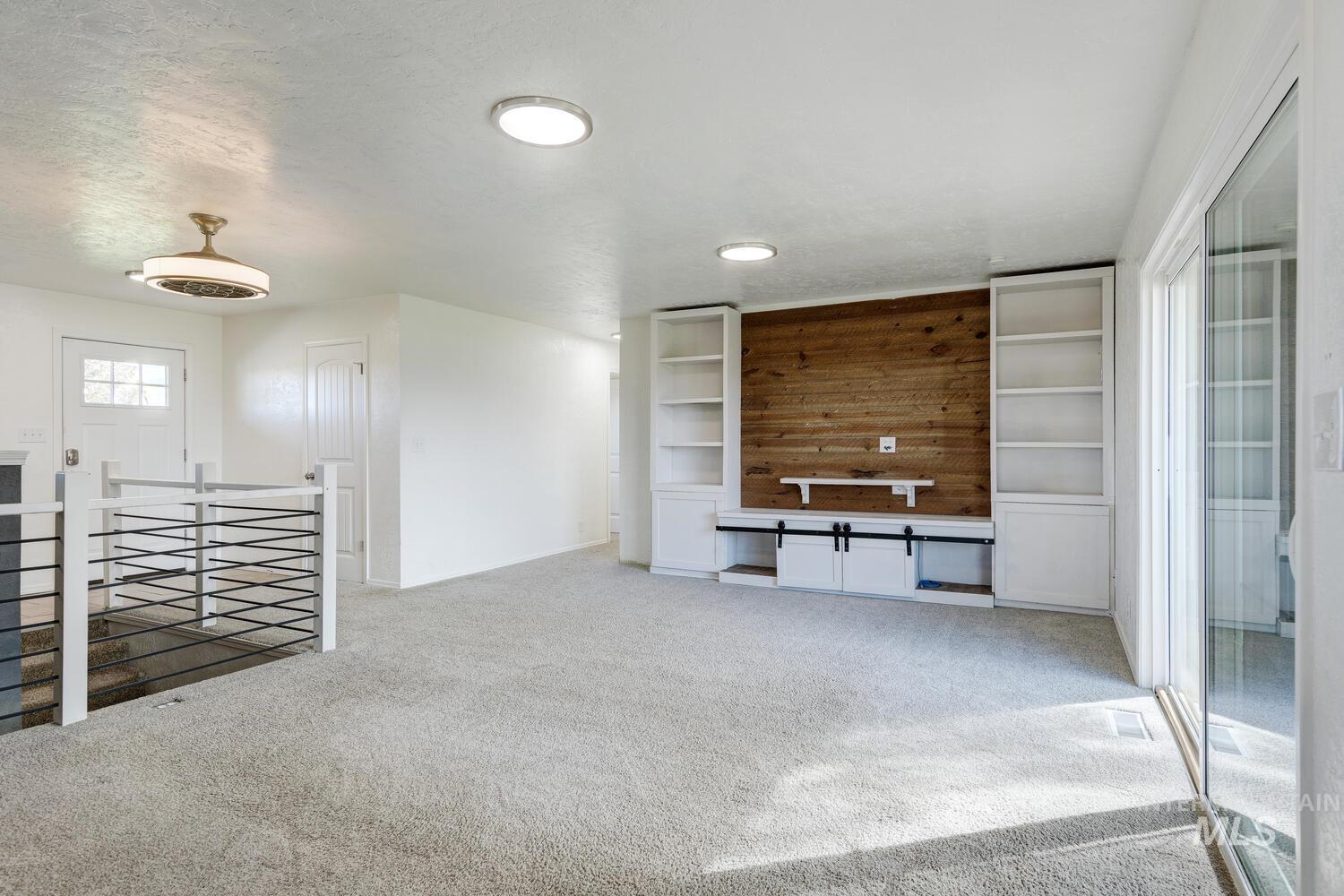 Unfurnished living room featuring light carpet and a textured ceiling
