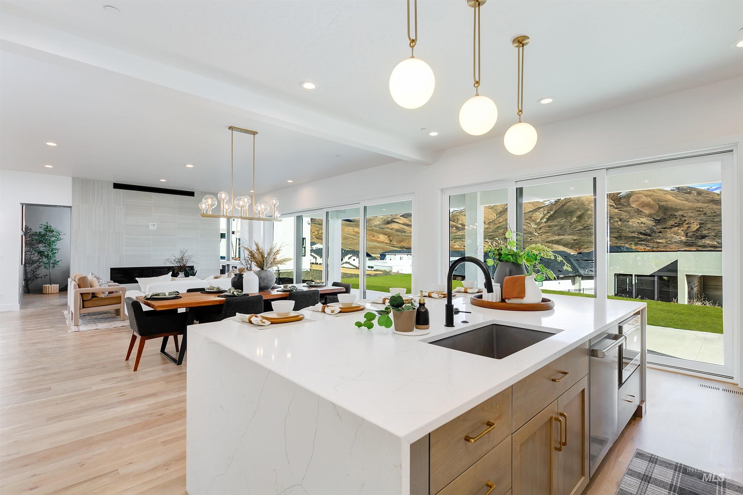 Kitchen with hanging light fixtures, light stone countertops, recessed lighting, open floor plan, and a large island with sink