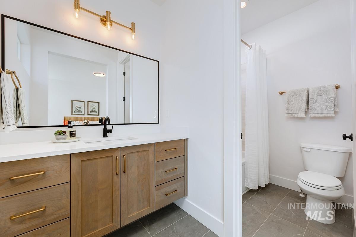Full bathroom with vanity, light tile patterned flooring, and shower / bath combo with shower curtain