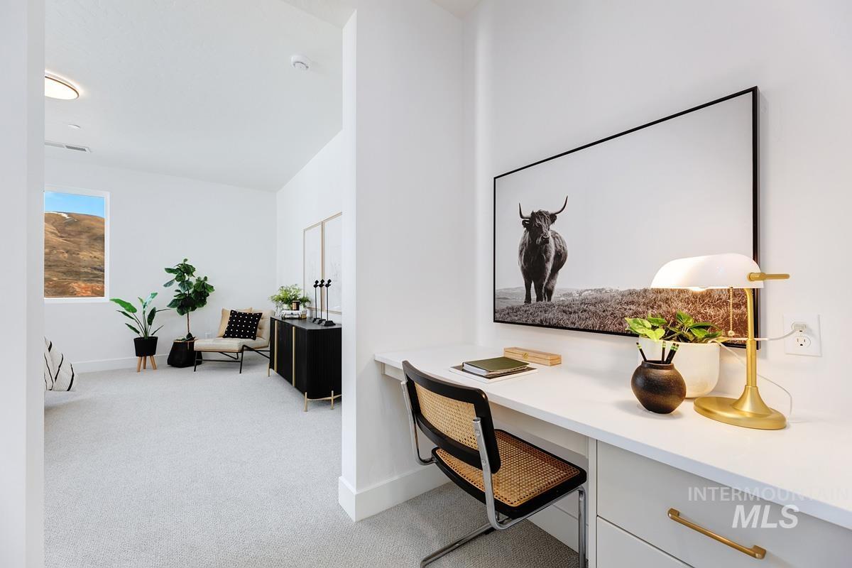 Office area with built in desk and light colored carpet