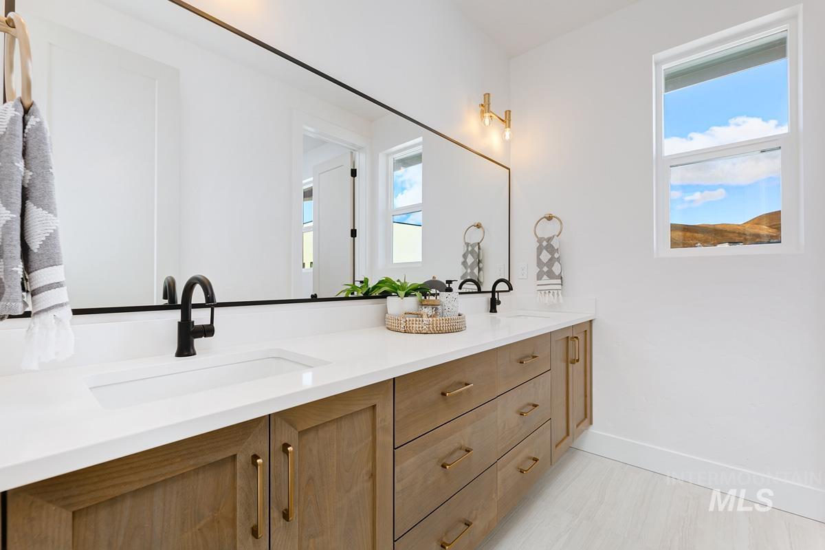 Full bath featuring double vanity and baseboards