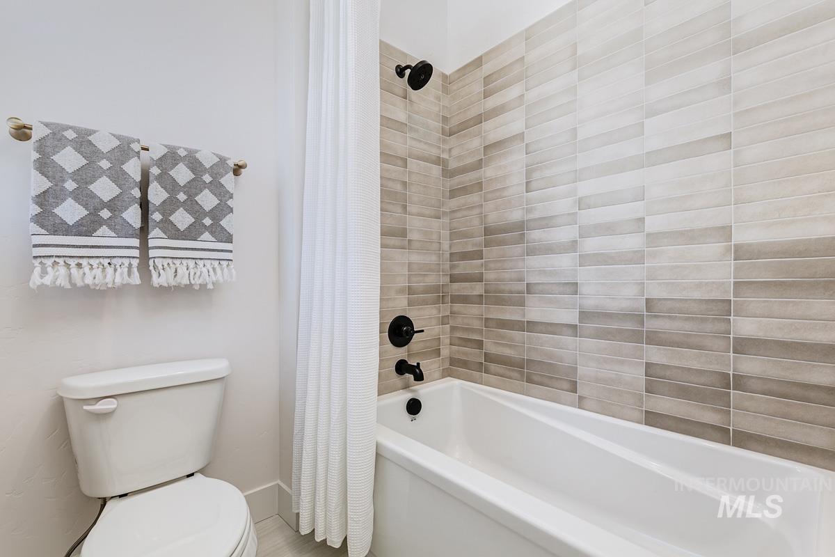 Full bathroom featuring shower / bath combo with shower curtain and toilet