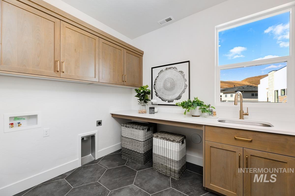 Washroom featuring electric dryer hookup, cabinet space, dark tile patterned flooring, and washer hookup