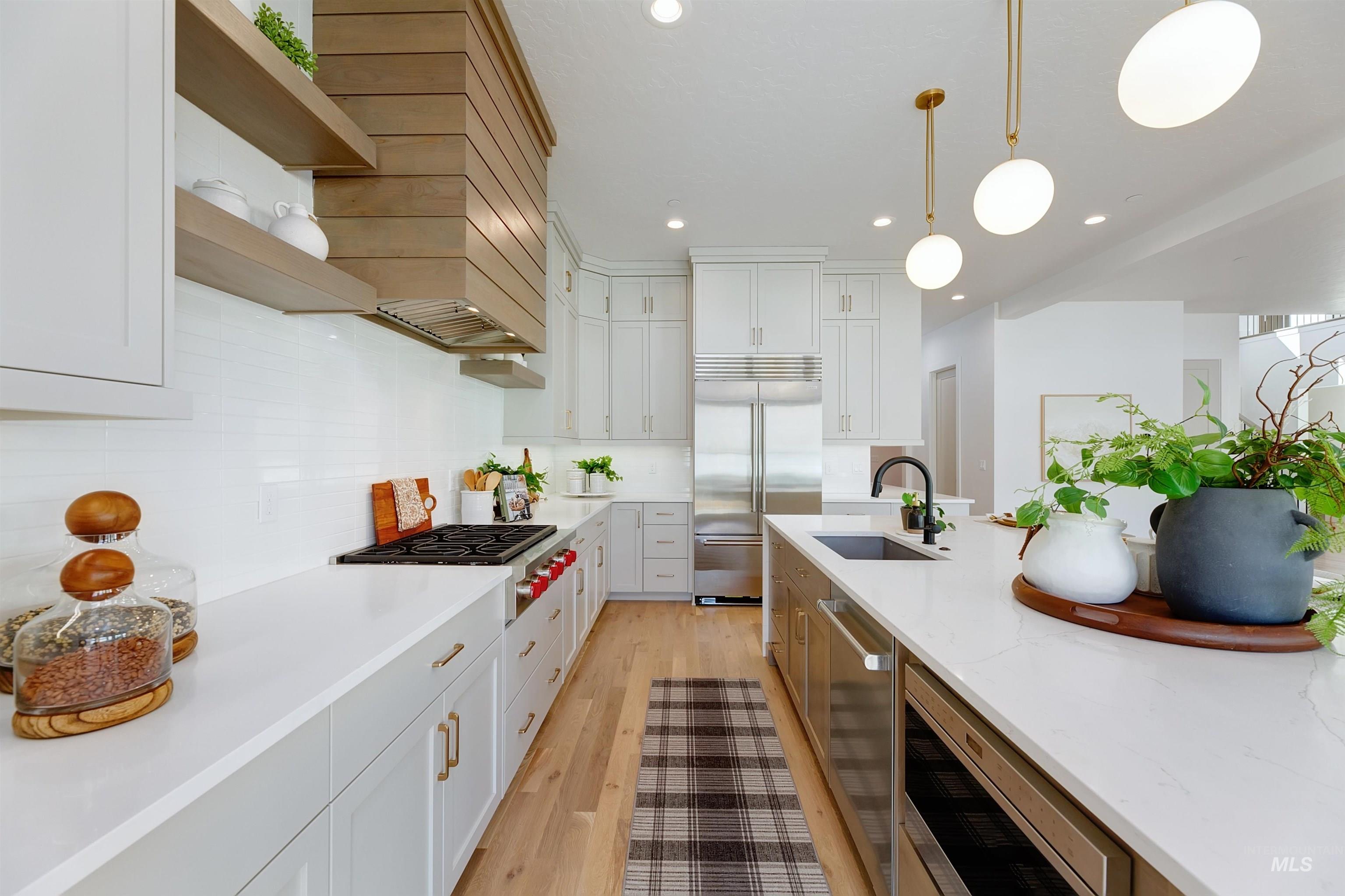 Kitchen featuring decorative light fixtures, light stone counters, tasteful backsplash, white cabinets, and light wood-style flooring