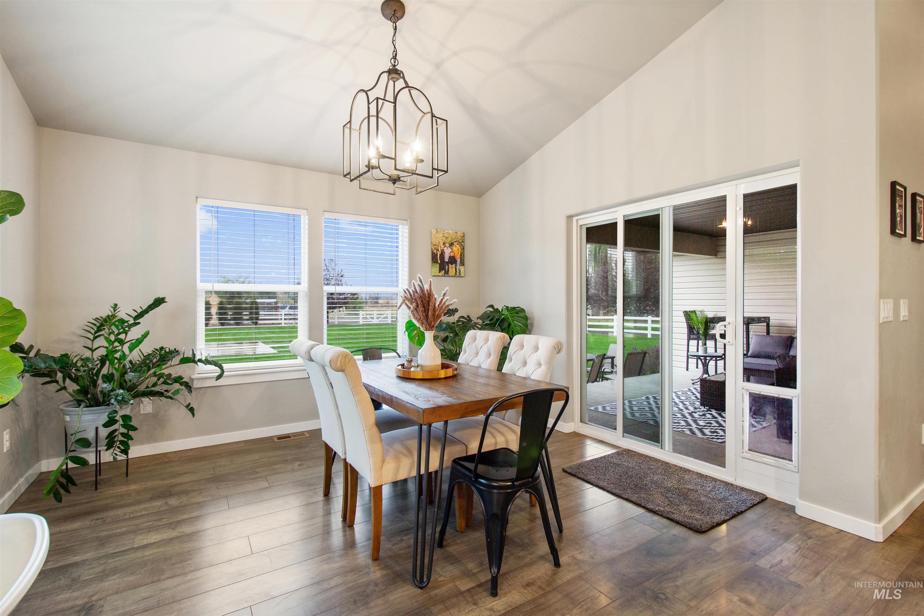 Dining space with lofted ceiling, dark wood-style flooring, and a chandelier