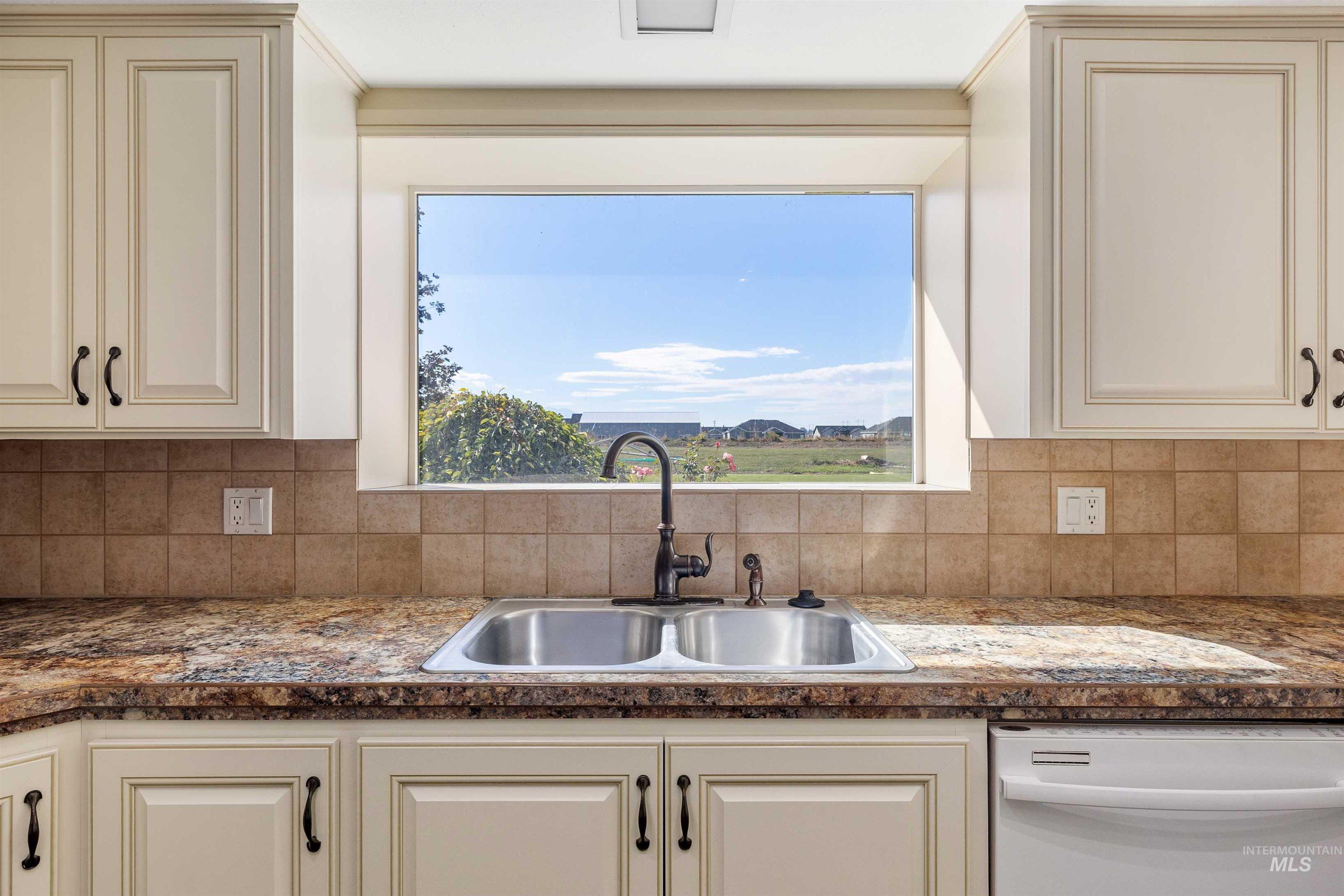Kitchen featuring dishwasher, cream cabinets, and backsplash