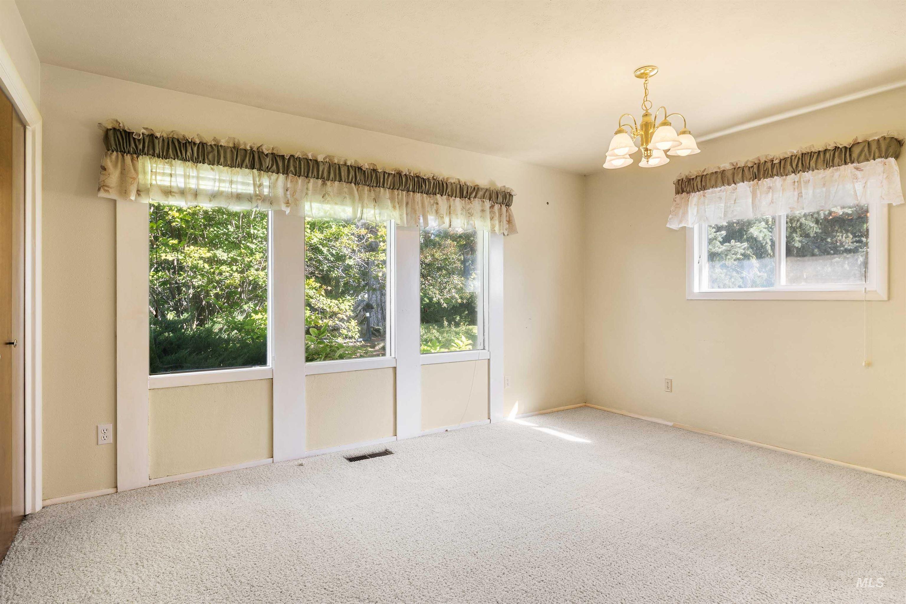 Carpeted spare room with a chandelier and baseboards
