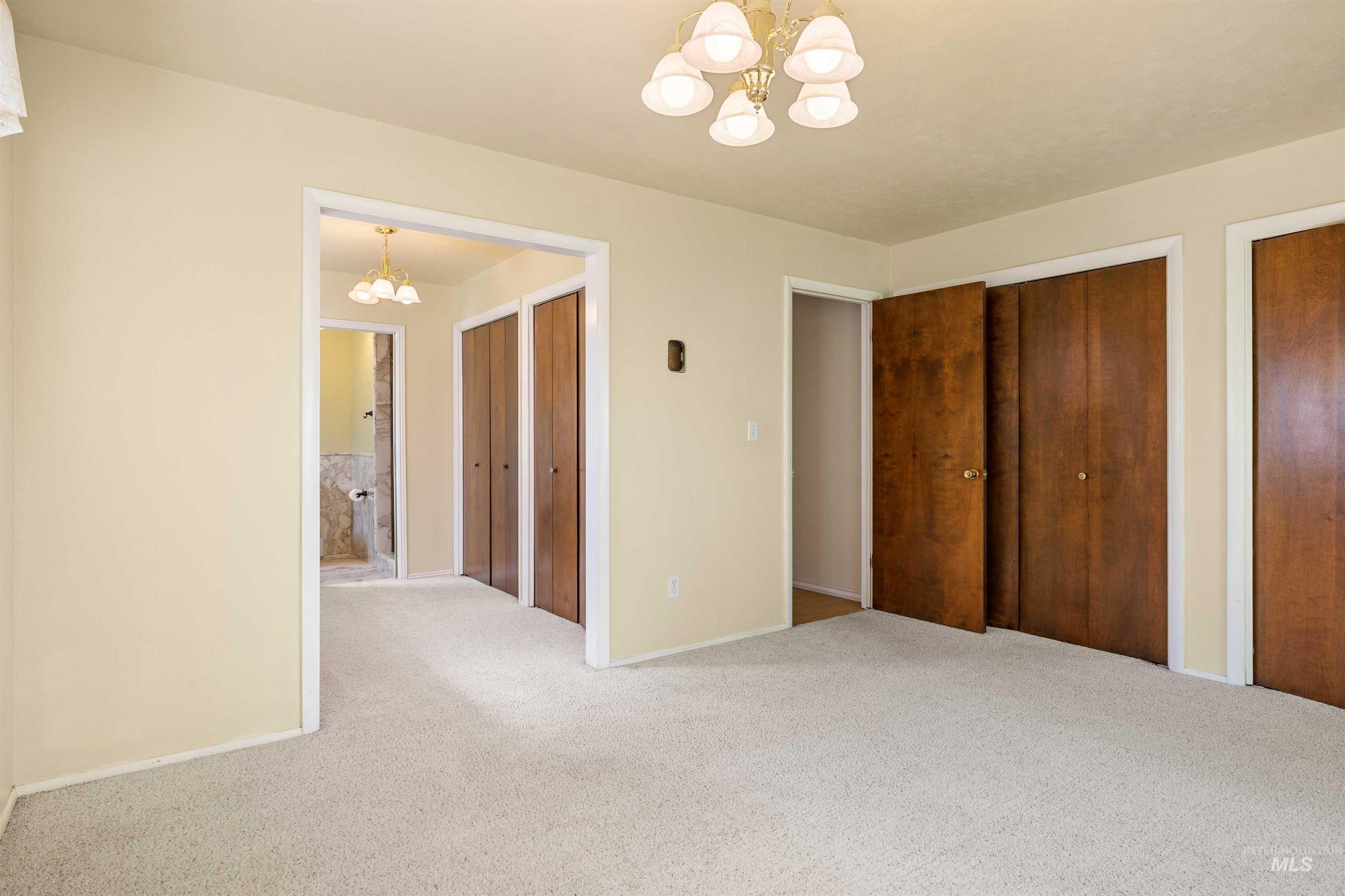 Unfurnished bedroom with a chandelier, two closets, and carpet flooring