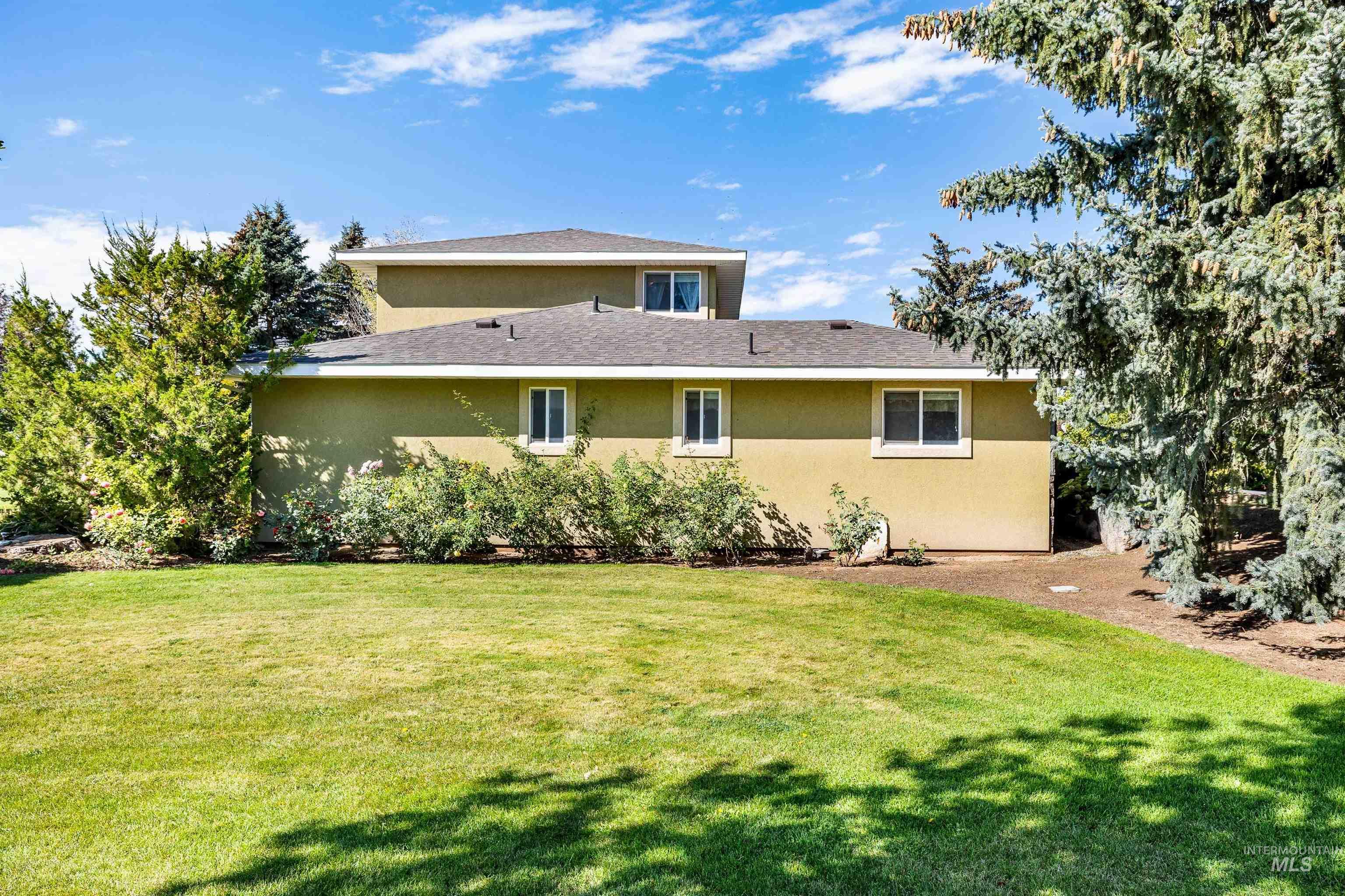 Rear view of property featuring a lawn, stucco siding, and roof with shingles