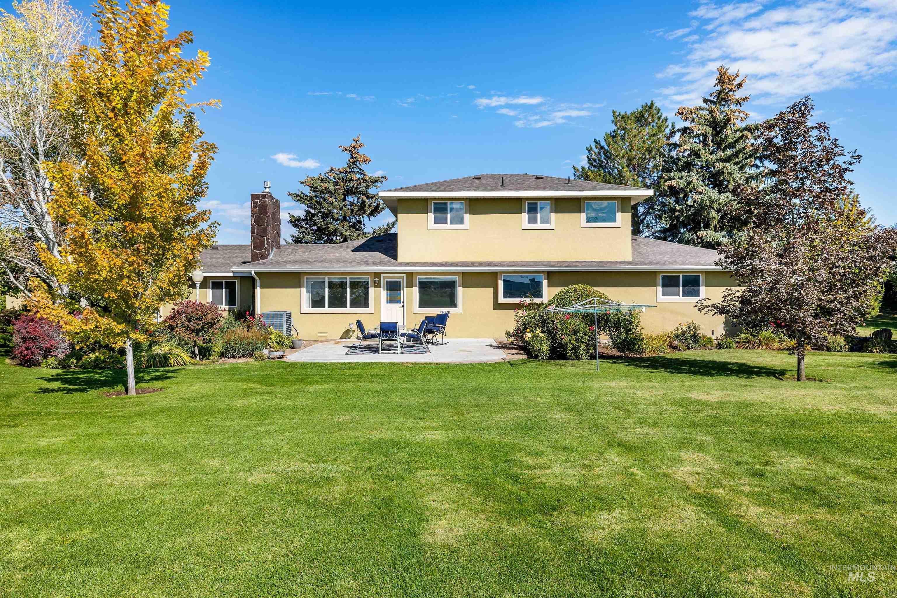 Back of house featuring a lawn, a patio area, a chimney, and stucco siding