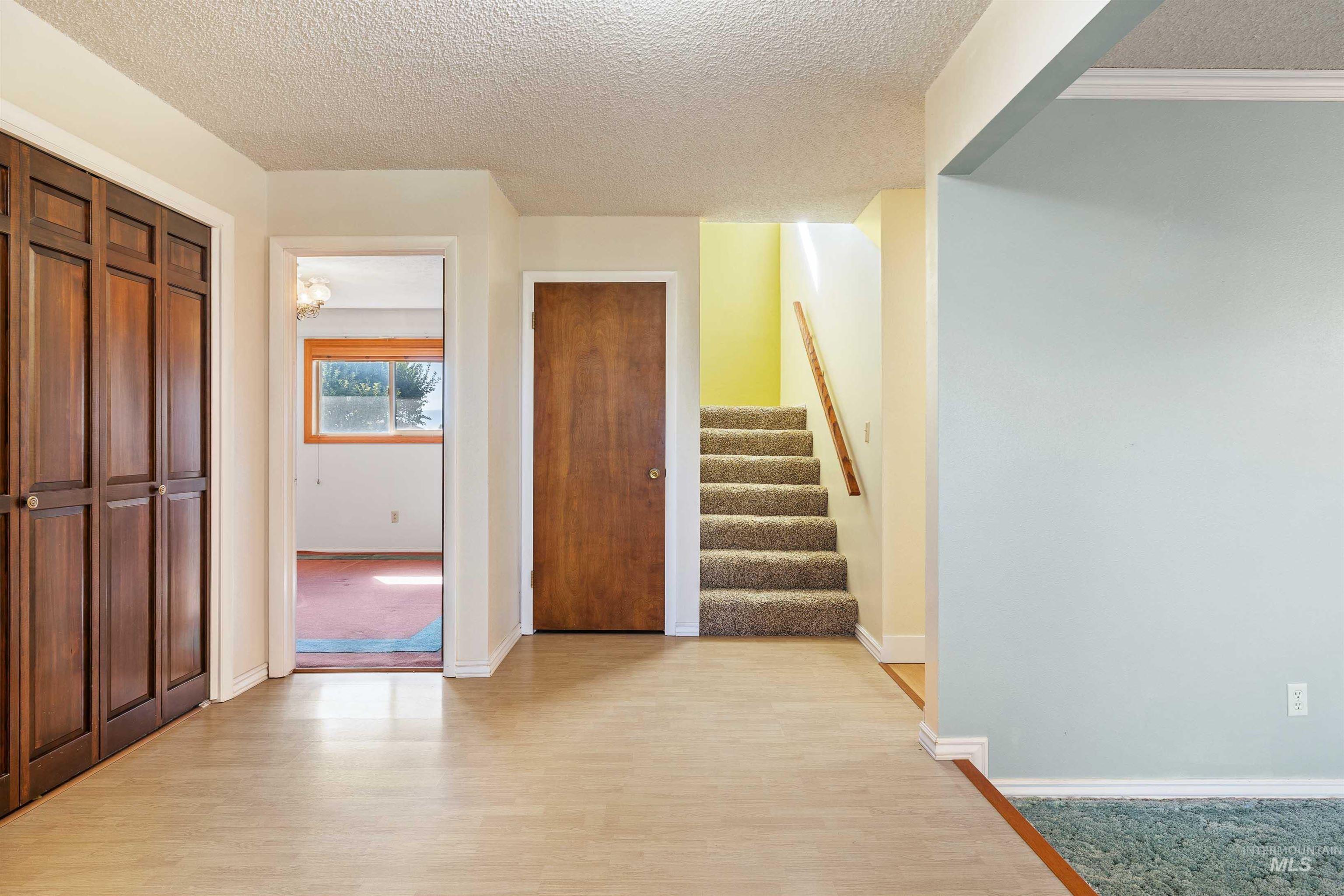 Entrance foyer with a textured ceiling, light wood-style floors, and stairway