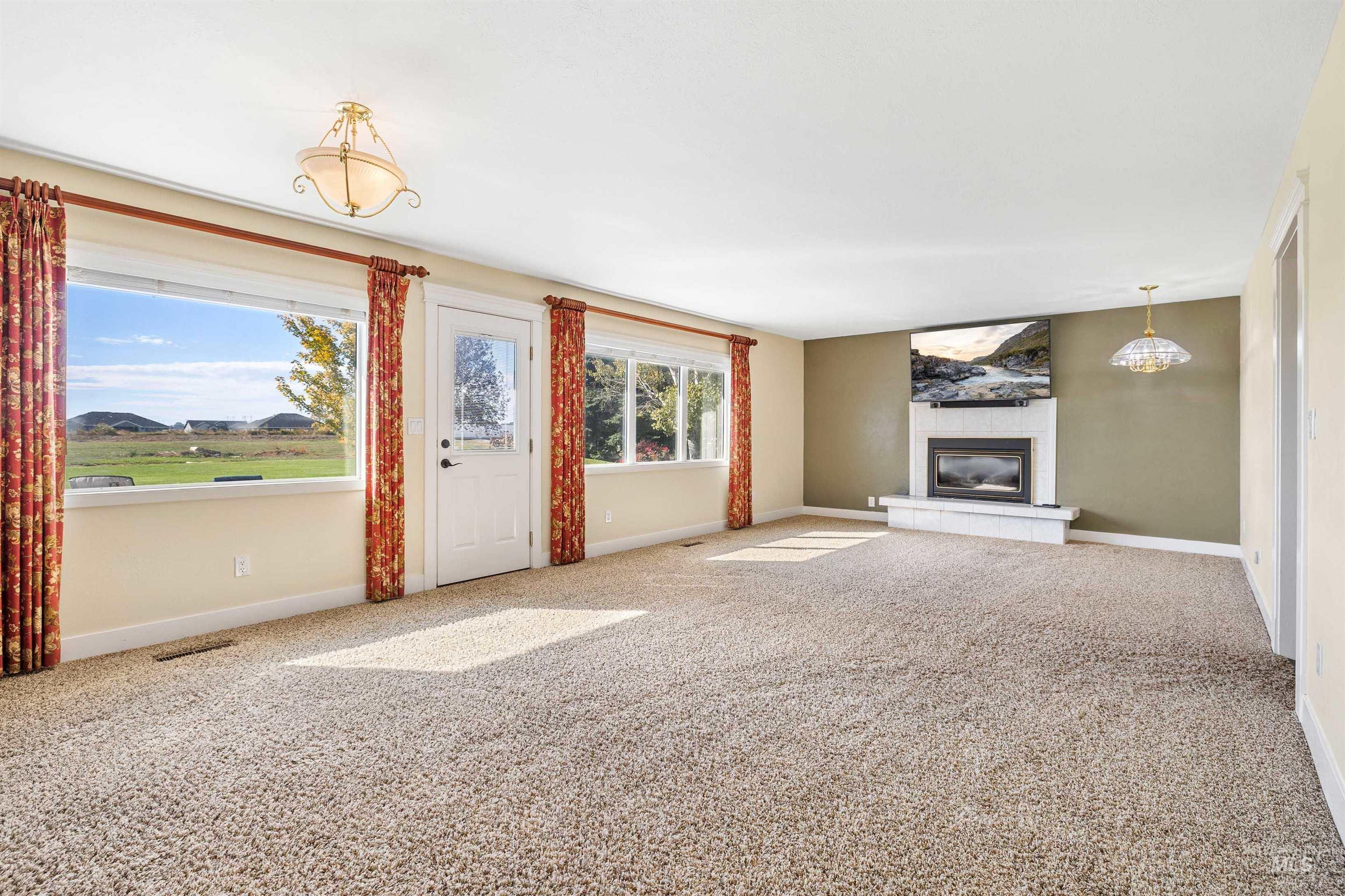 Unfurnished living room with carpet floors and a tiled fireplace
