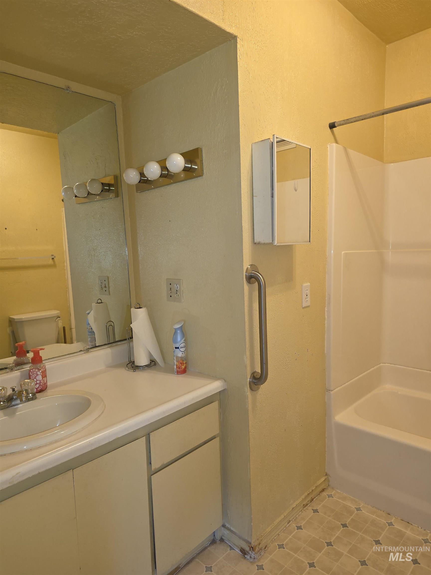 Bathroom featuring vanity, tub / shower combination, and light tile patterned floors