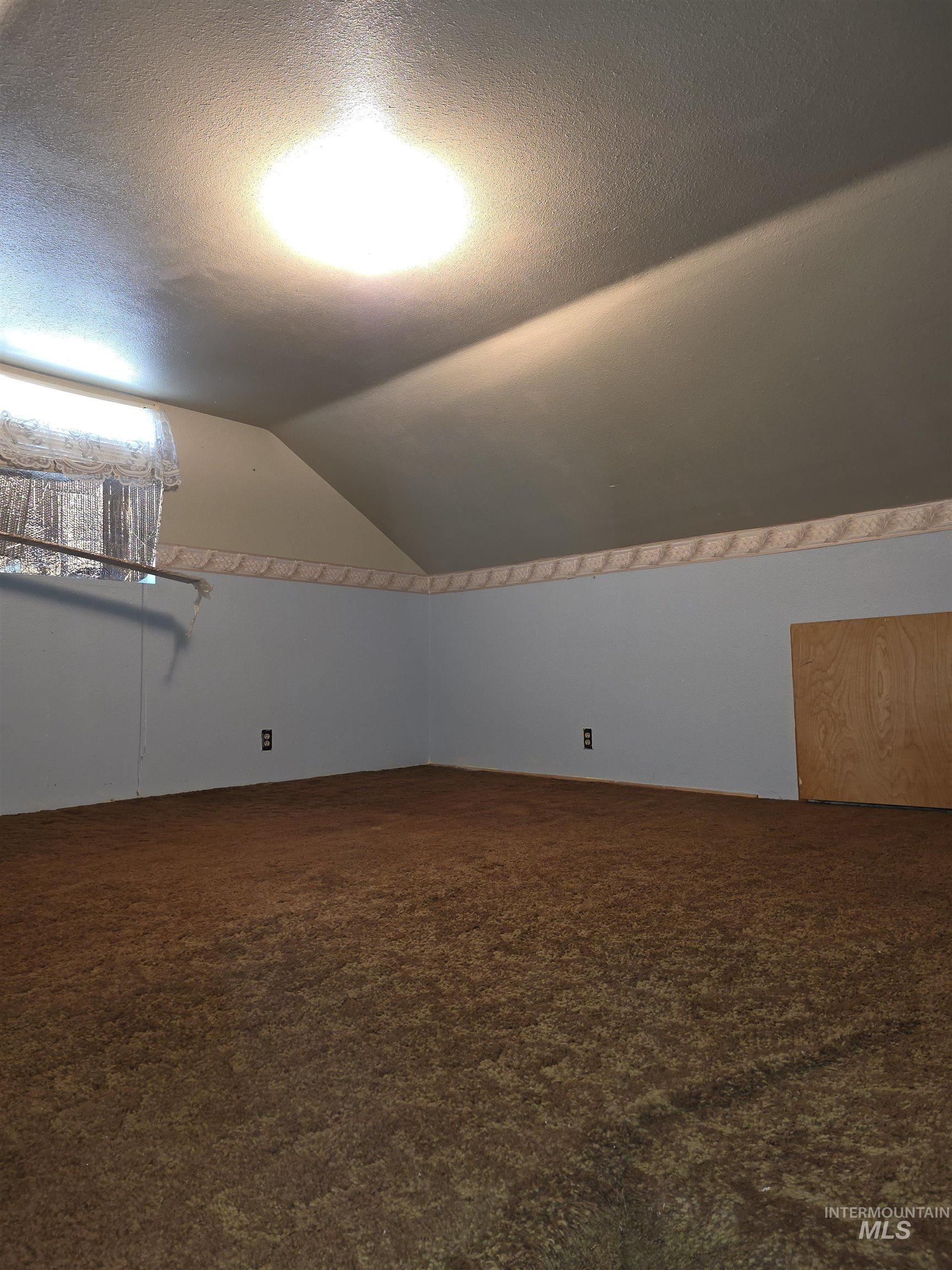Additional living space with vaulted ceiling, a textured ceiling, and dark carpet