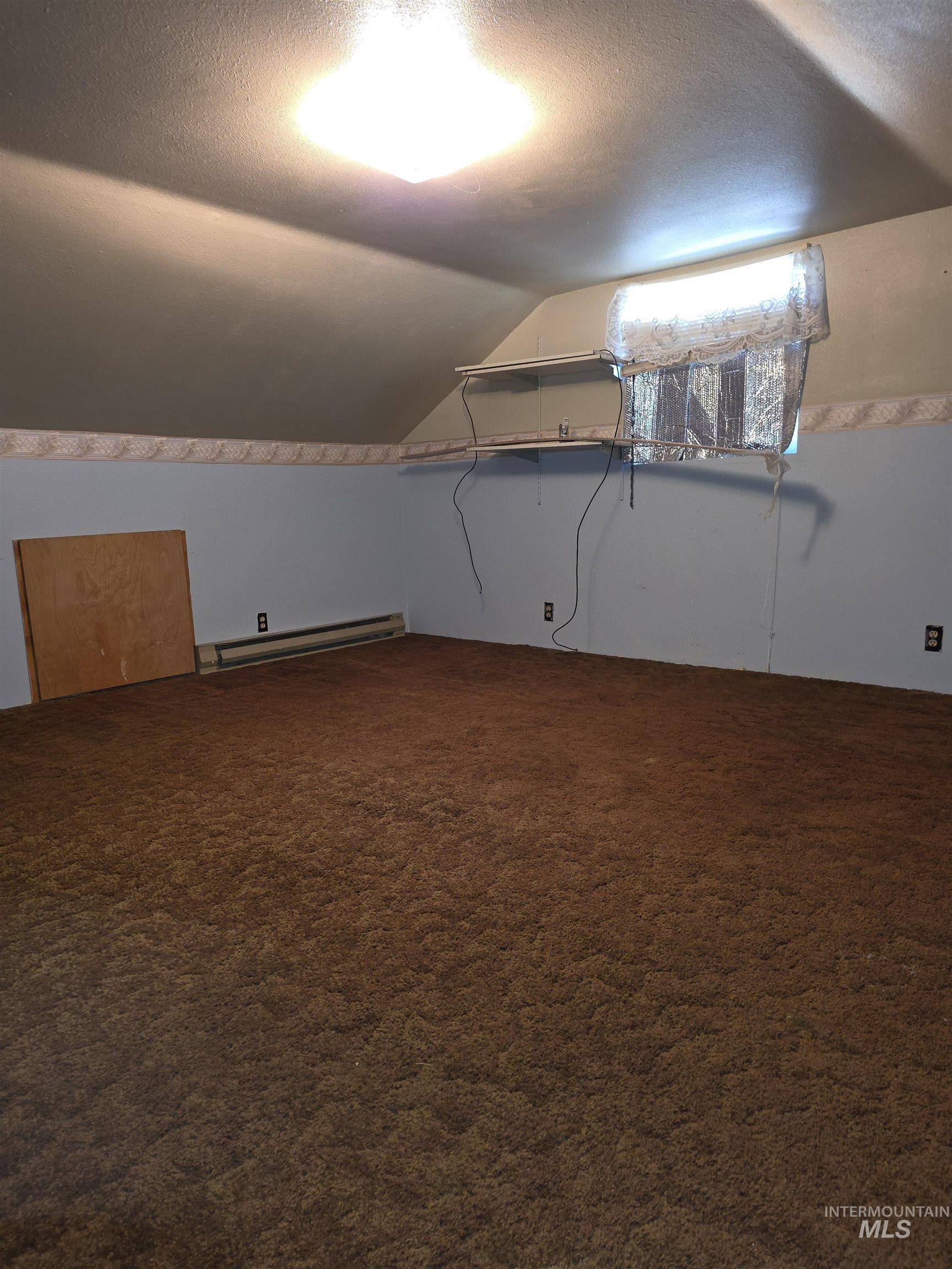 Bonus room featuring vaulted ceiling, dark colored carpet, a textured ceiling, and a baseboard radiator