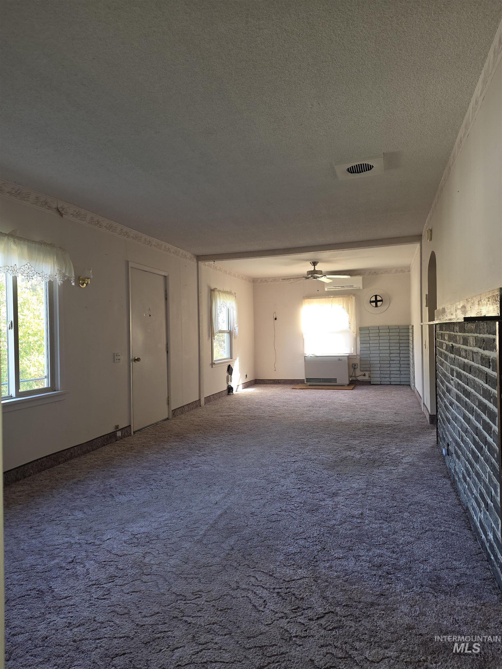 Empty room with dark colored carpet, a textured ceiling, and ceiling fan