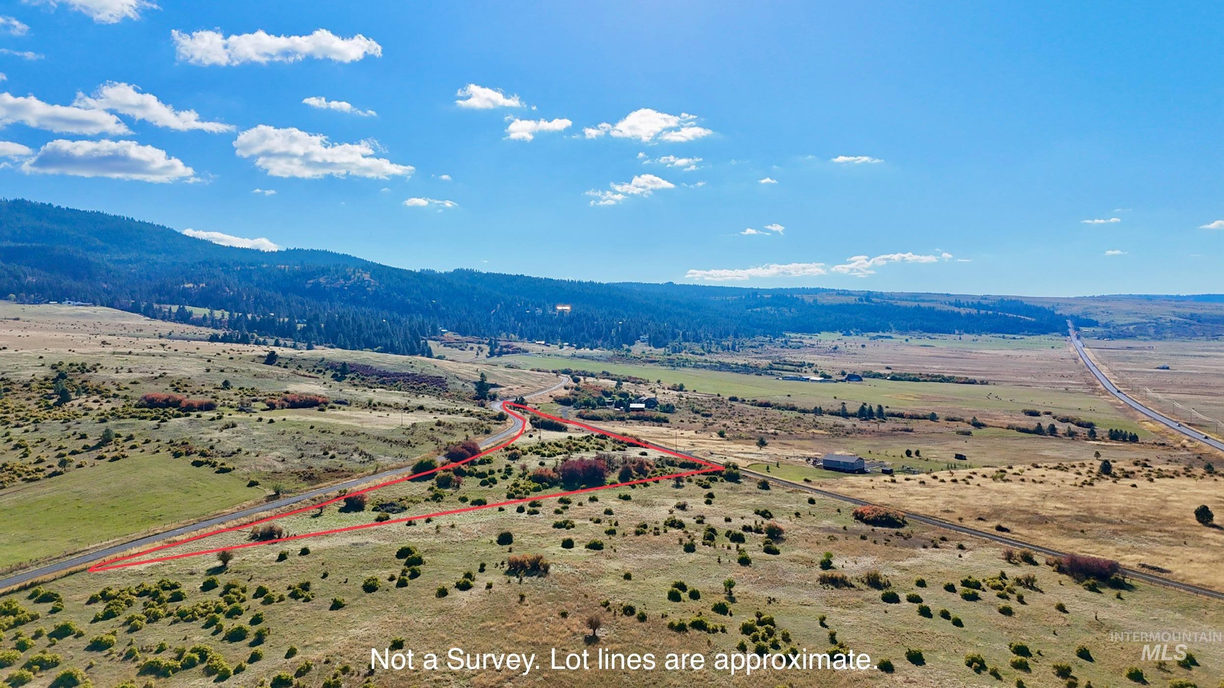 Aerial view of sparsely populated area featuring property parcel outlined and a mountainous background