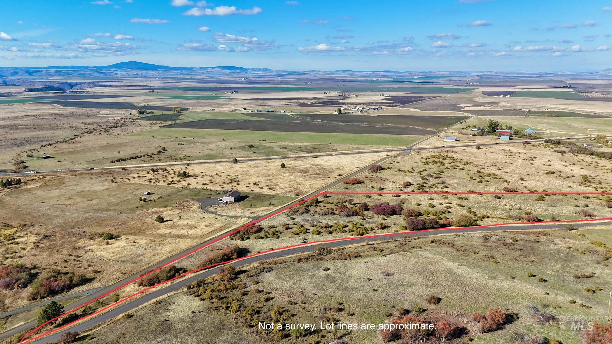 Aerial view of sparsely populated area with property parcel outlined and a mountainous background