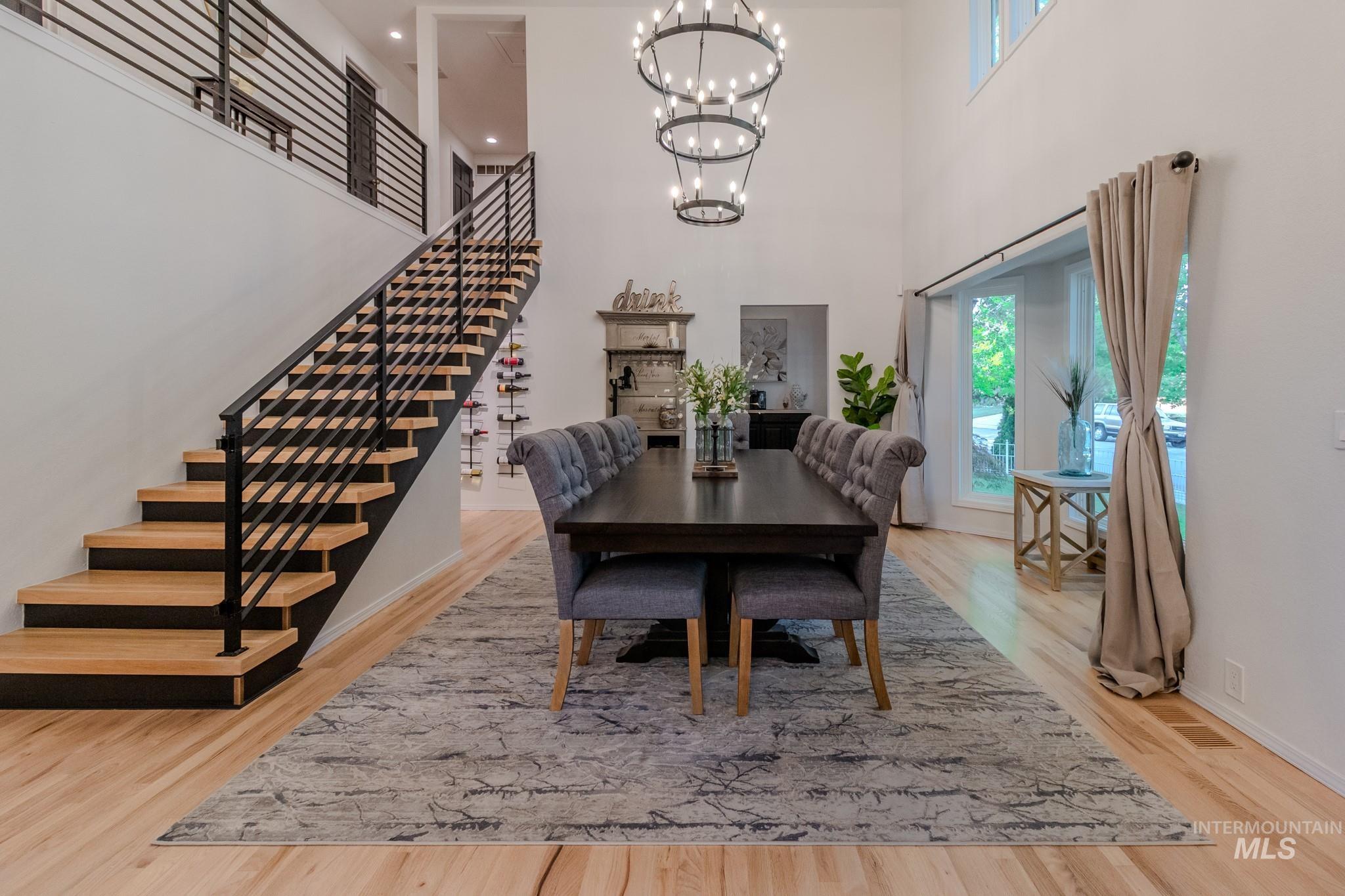 Dining area featuring stairs, a chandelier, a towering ceiling, and wood finished floors