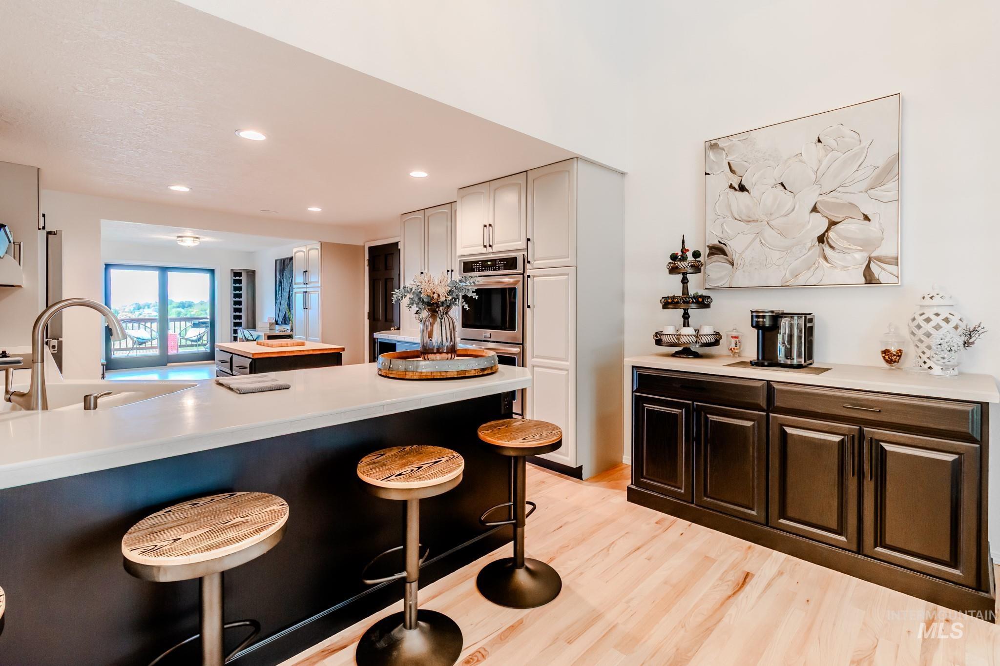 Kitchen featuring a kitchen breakfast bar, light countertops, light wood finished floors, double oven, and recessed lighting