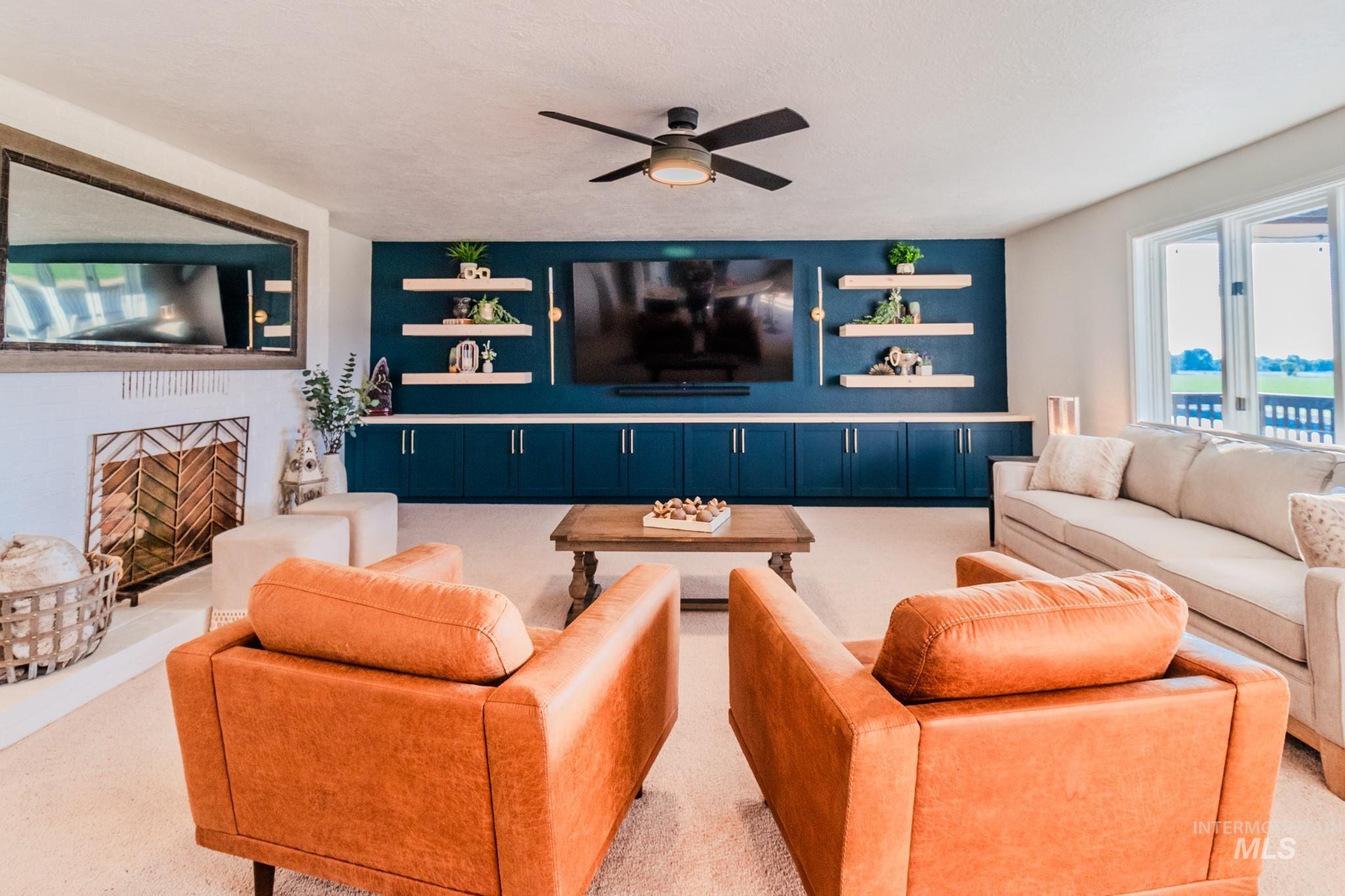 Carpeted living area featuring ceiling fan and a fireplace with raised hearth
