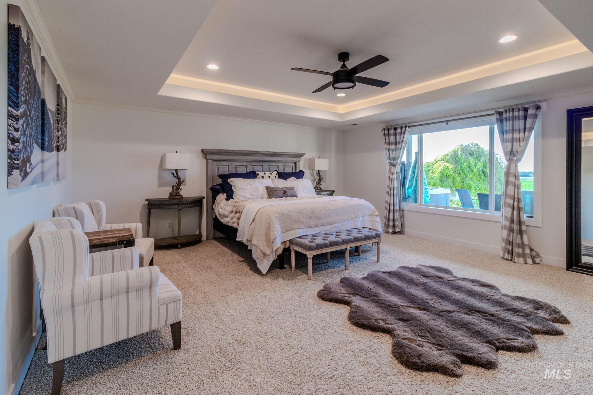 Carpeted bedroom featuring a raised ceiling, recessed lighting, and ceiling fan