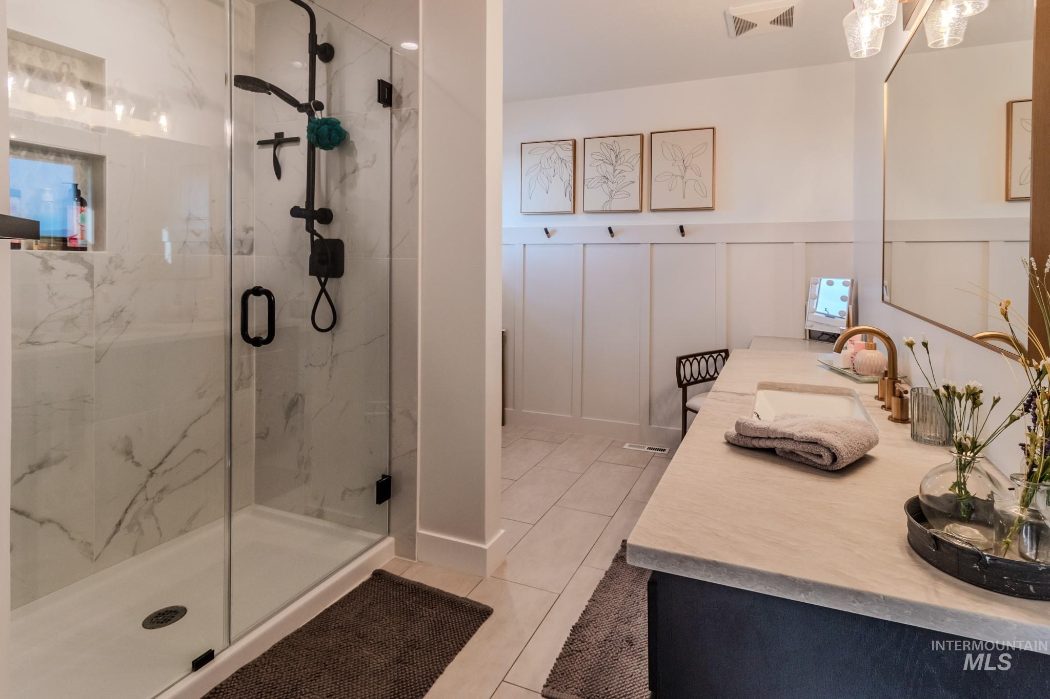 Bathroom with tile patterned flooring, a marble finish shower, and double vanity