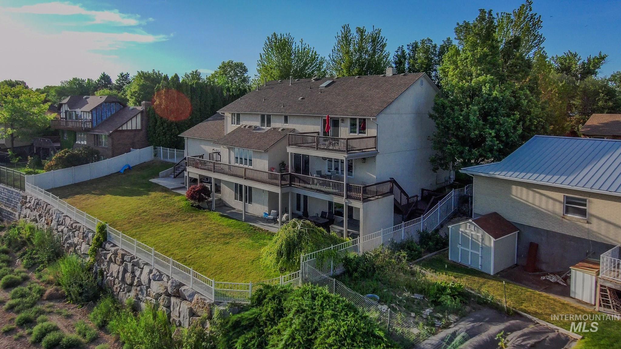 Rear view of house featuring a storage unit, a fenced backyard, and stairway