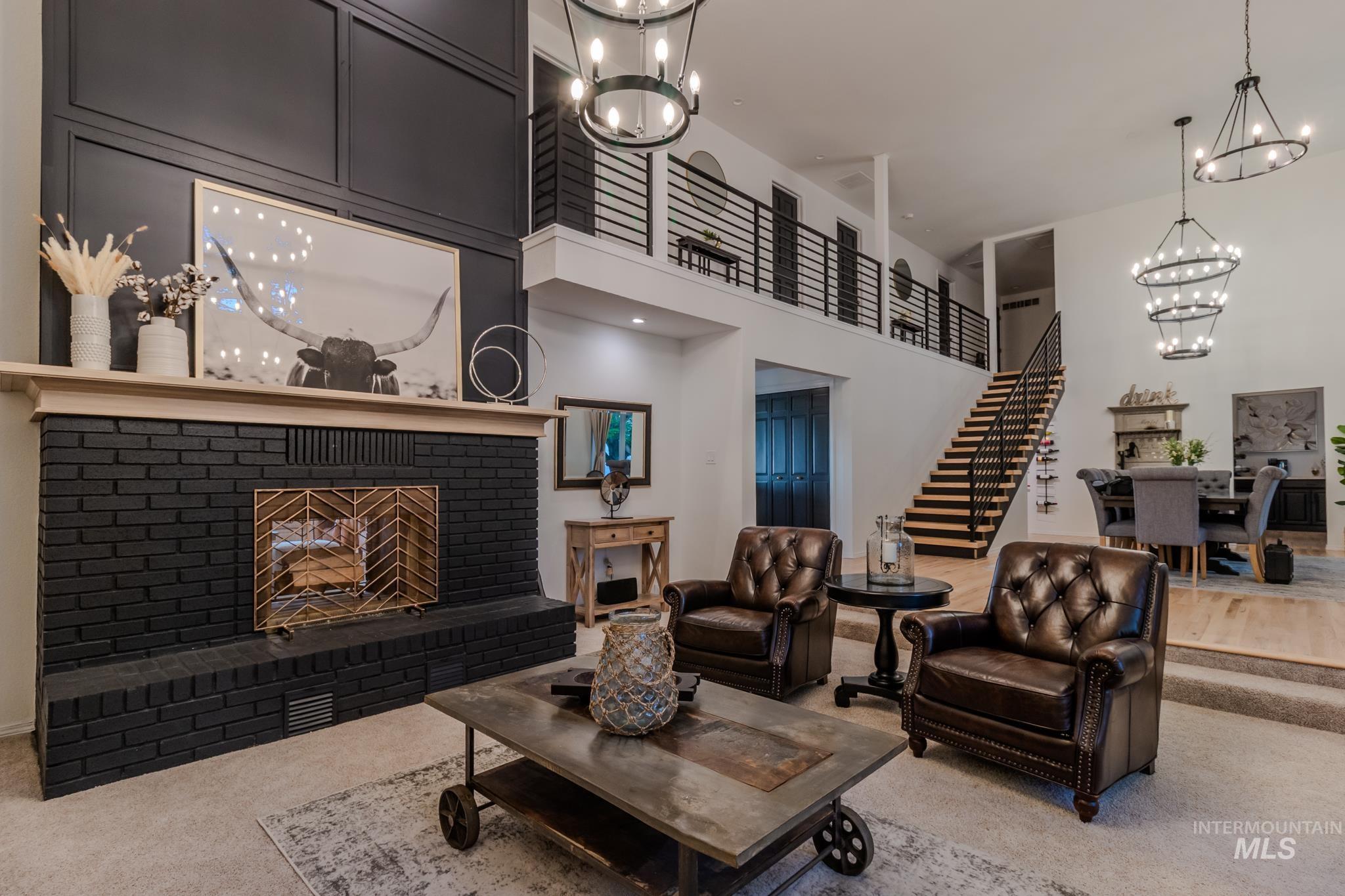 Carpeted living room featuring a chandelier, stairs, a brick fireplace, and a high ceiling
