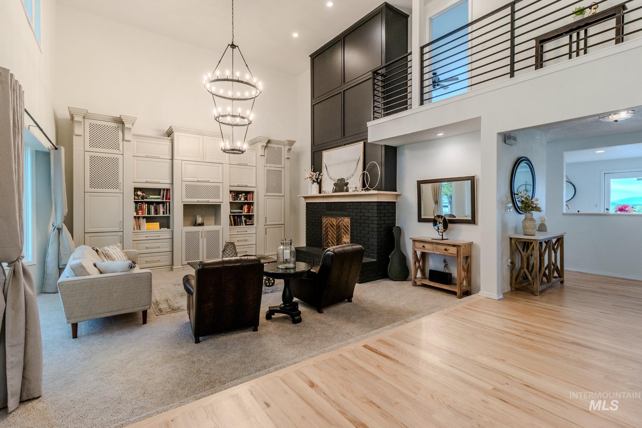 Living area with a high ceiling, light wood-style flooring, a chandelier, and a fireplace
