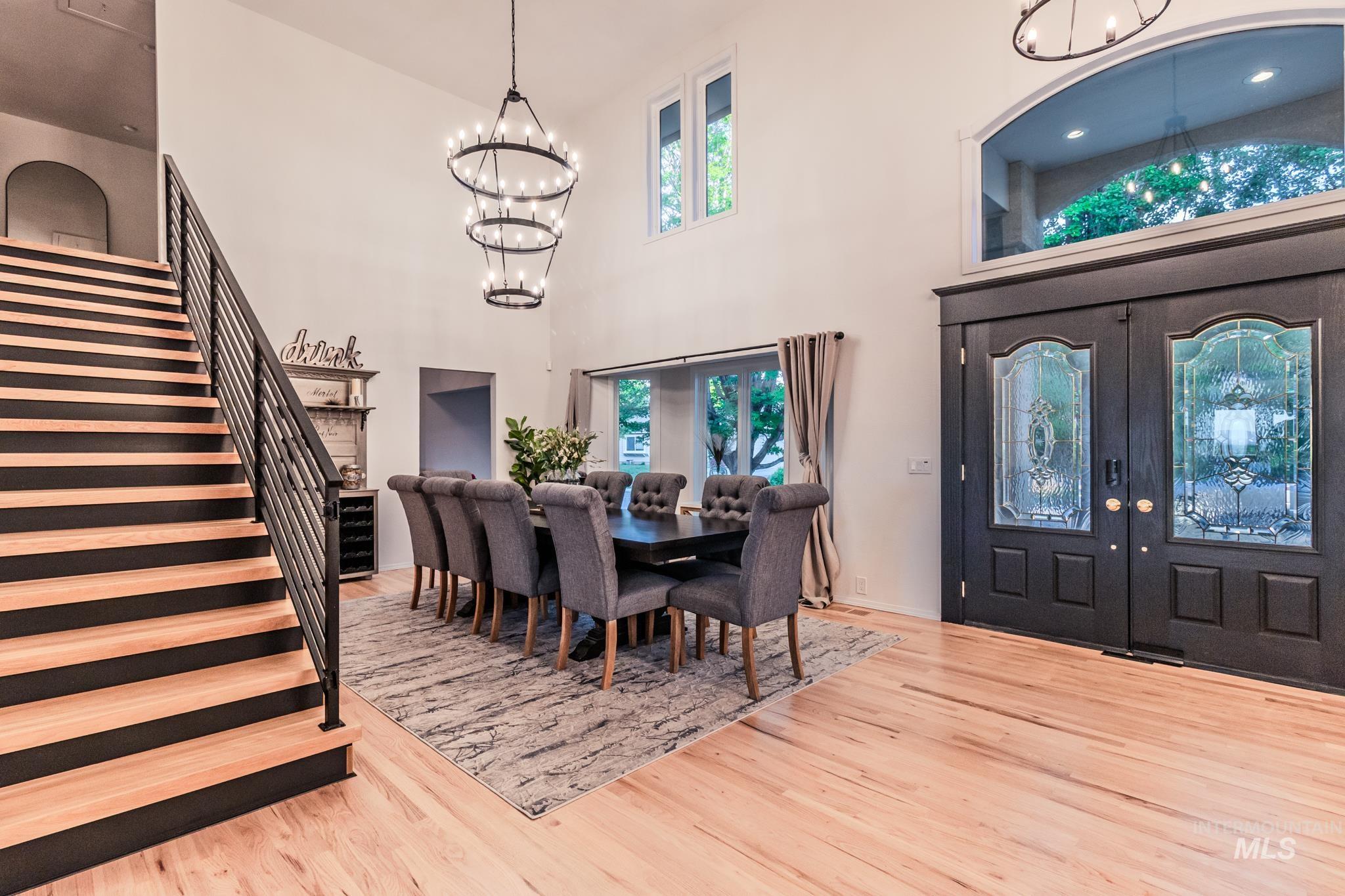 Dining area with a chandelier, stairway, wood finished floors, a towering ceiling, and french doors