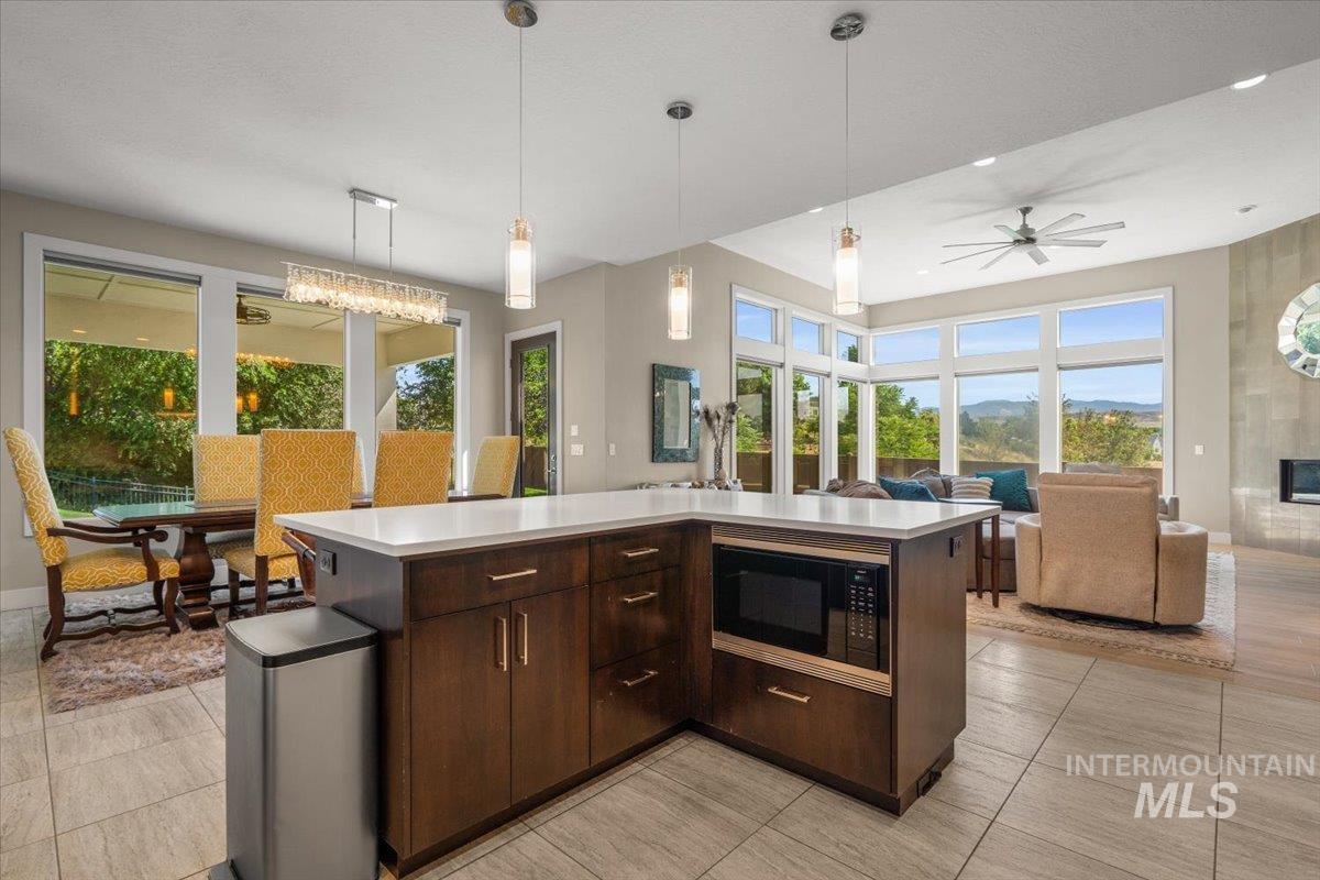 Kitchen featuring black microwave, open floor plan, light countertops, dark brown cabinetry, and a ceiling fan