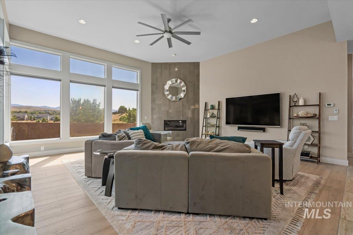 Living room with ceiling fan, plenty of natural light, recessed lighting, a fireplace, and light wood-style floors